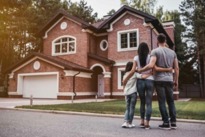 Family hugging in front of new home